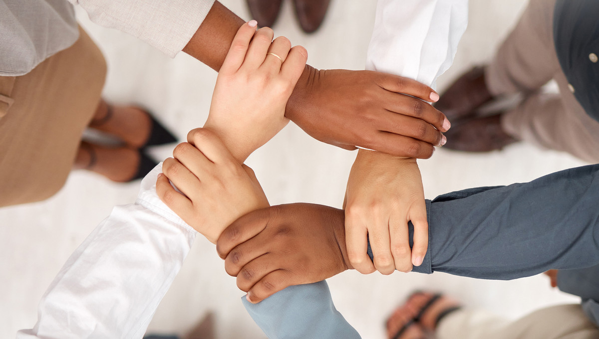 Equipo de Synergias uniendo las manos en señal de trabajo en equipo
